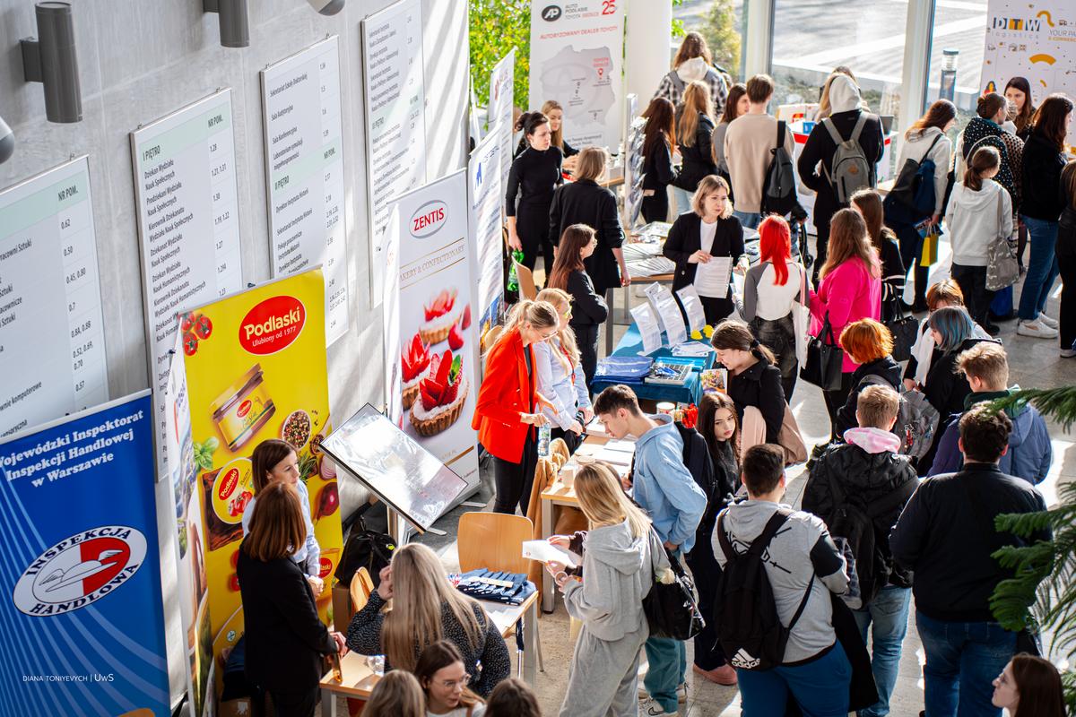 Studenci i wystawcy tłumnie biorą udział w giełdzie. Studenci podchodzą do stoisk na korytarzu wydziału Społecznego UwS.
