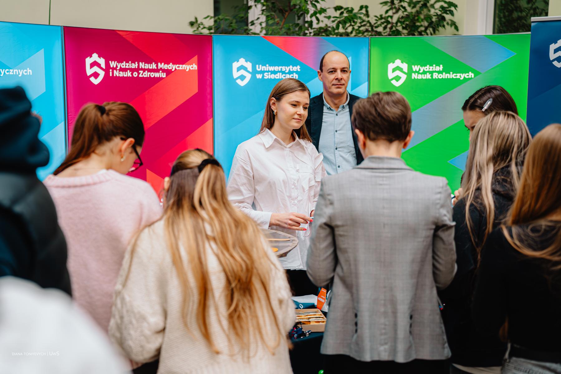 Studenci i pracownicy na stoisku zachęcają młodzież do skorzystania z oferty UwS.